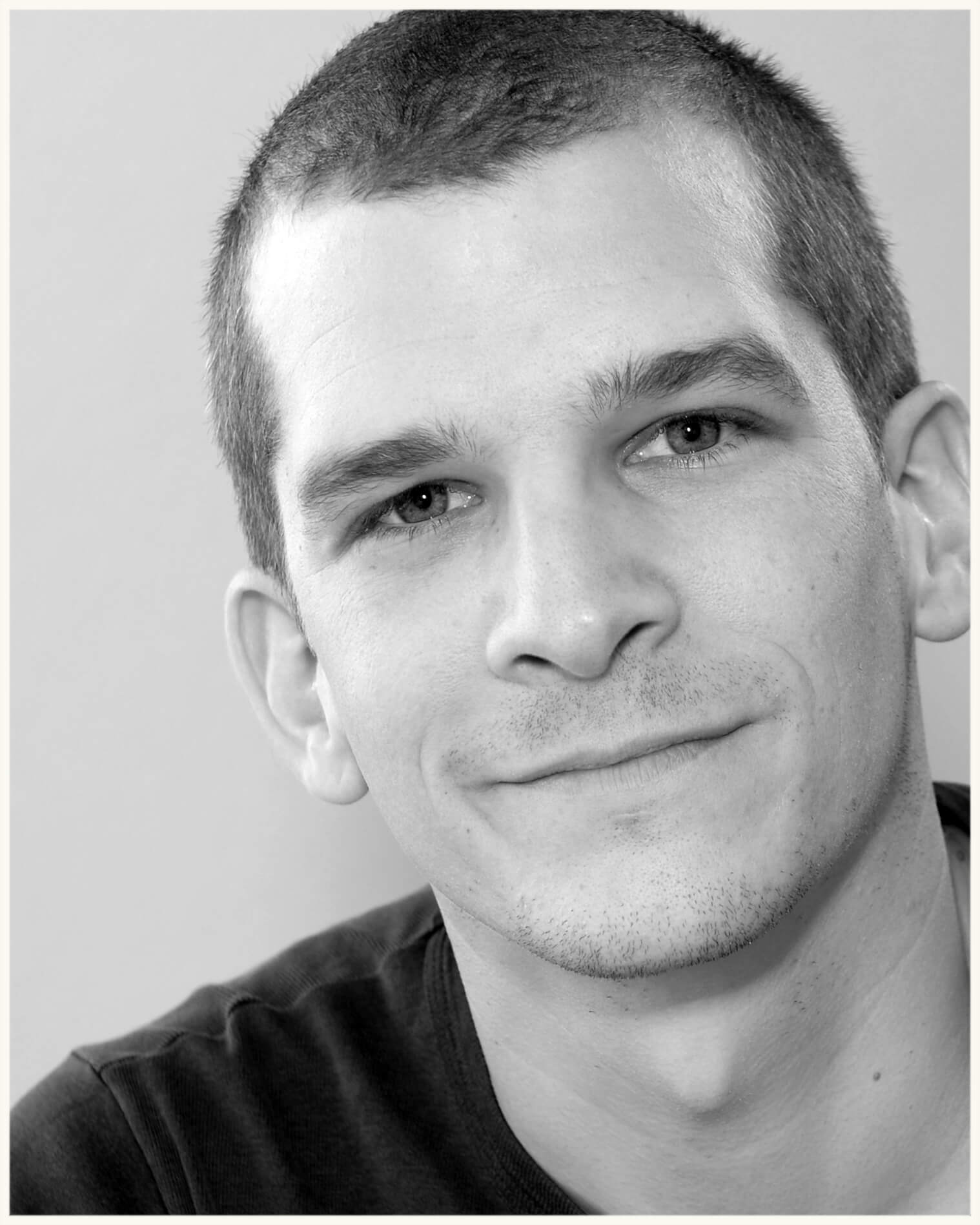 Porträt von Markus Hasler, lächelnd vor neutralem Hintergrund. schwarz/weiss